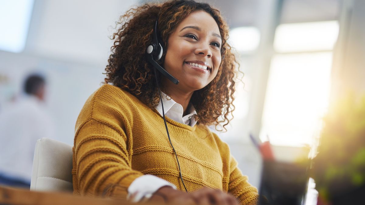 A smiling professional wearing a headset on a call