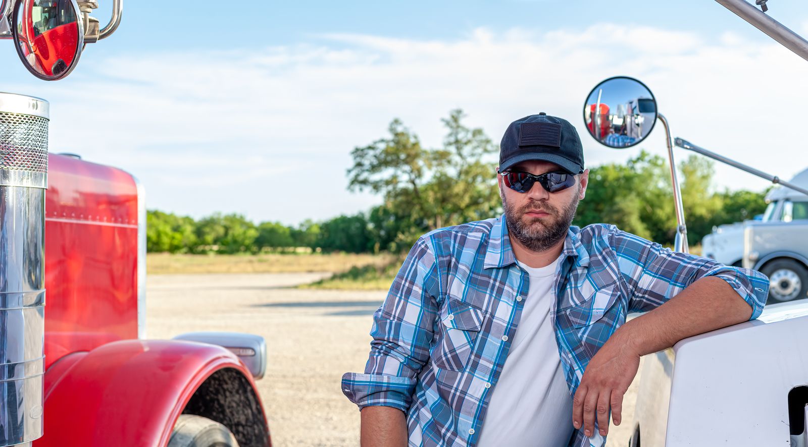 A truck driver leaning against a red American semi