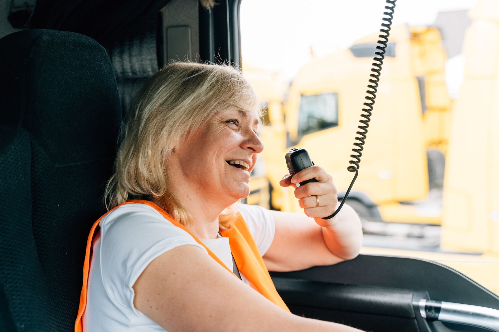 A woman truck driver talking on the CB radio in her cab
